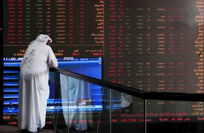 A Kuwaiti trader checks stock prices at Boursa Kuwait in Kuwait City, on March 8, 2020. - Kuwait Boursa authorities stopped trading after the Premier Index slumped 10 percent while the All-Sh