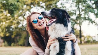 Dog wearing harness and being hugged by woman