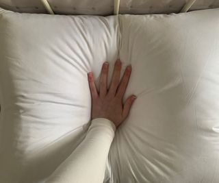 A hand pressing down on the Brooklinen Down Pillow.