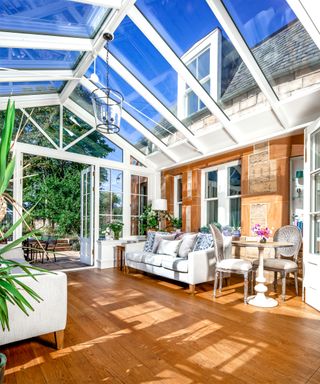 white conservatory with wooden floor attached to stone house