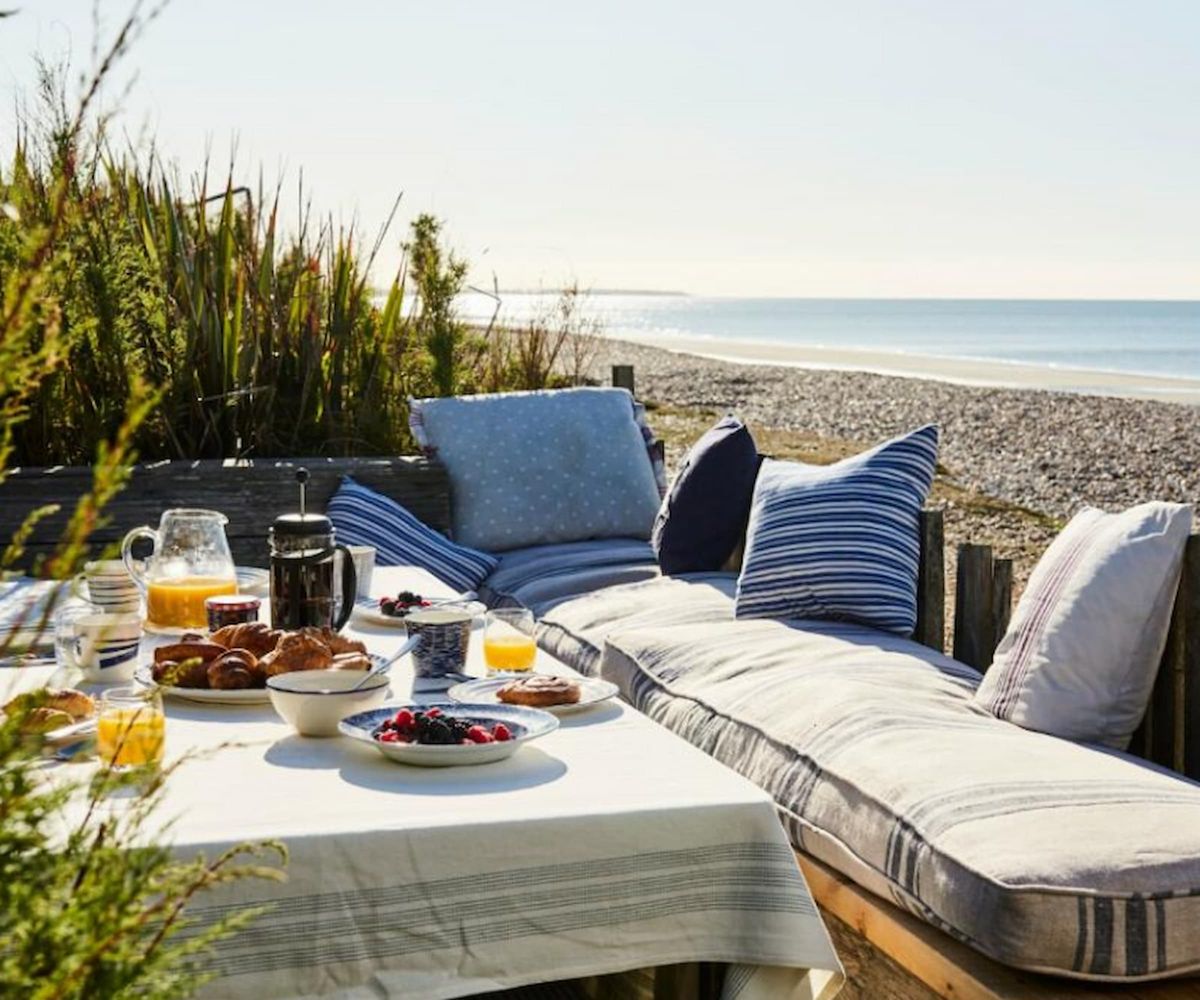 A breakfast table in a garden looking over the beach