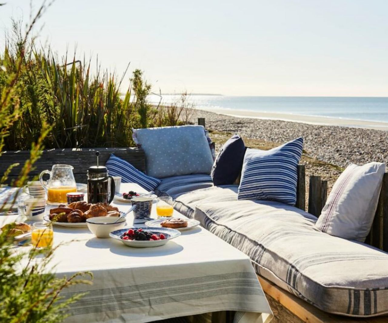 A breakfast table in a garden looking over the beach