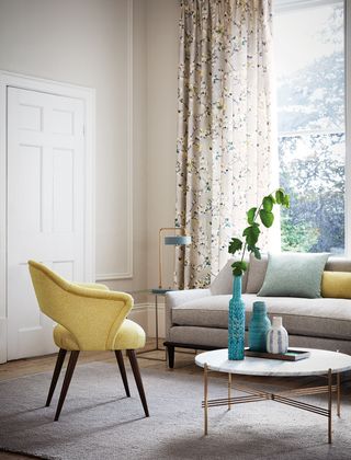 Oriental flower print curtains in elegant lounge setting, with blue vessels and greenery on coffee table.