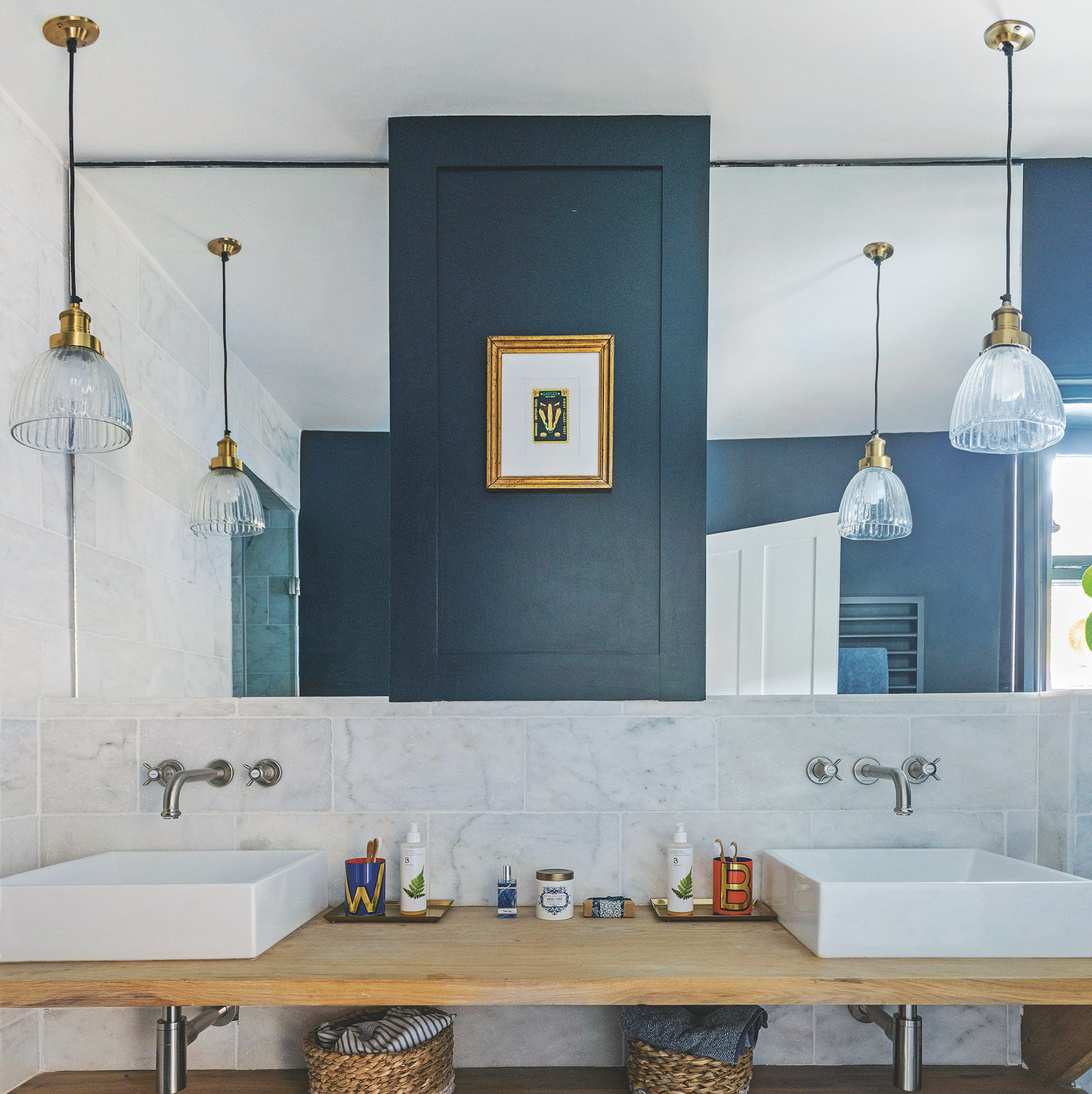 blue bathroom with wooden counter and glass pendants in front of mirrors