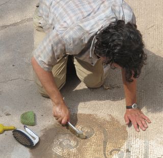 Slowly, bit by bit, the mosaic floors of the building are being revealed.