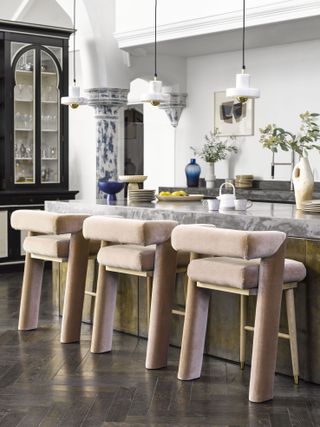 grand kitchen with marble worktop, gold detailing, pendant lights, velvet bar stools