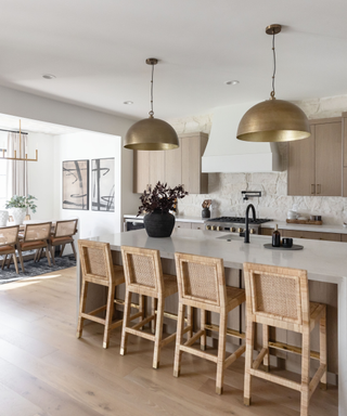 Neutral open plan kitchen dining space with large kitchen island, exposed brick backsplash and round brass pendant lighting