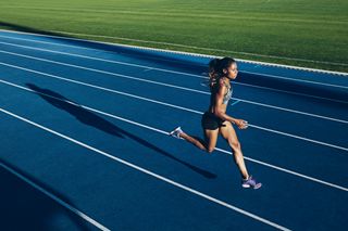 Outdoor shot of young African woman athlete running on racetrack. Professional sportswoman during running training session how to run for longer.