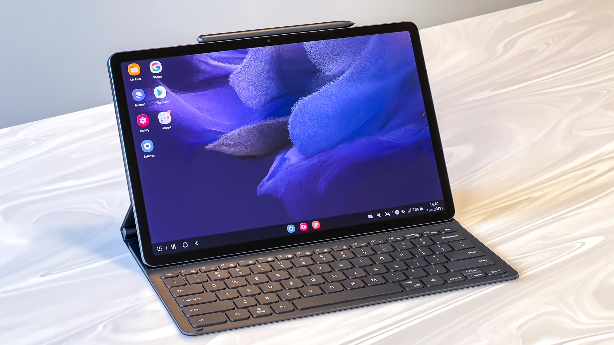 The Samsung Galaxy Tab S7 FE stood on a table with its keyboard cover and an S Pen magnetically attached to the top