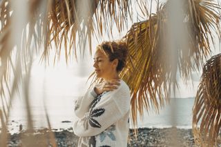 A woman hugs herself on a beach