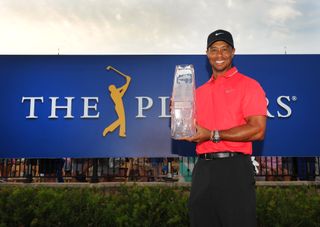 Tiger Woods holds The Players Championship trophy in front of The Players Championship board