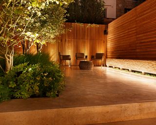 lit courtyard garden with seats at night