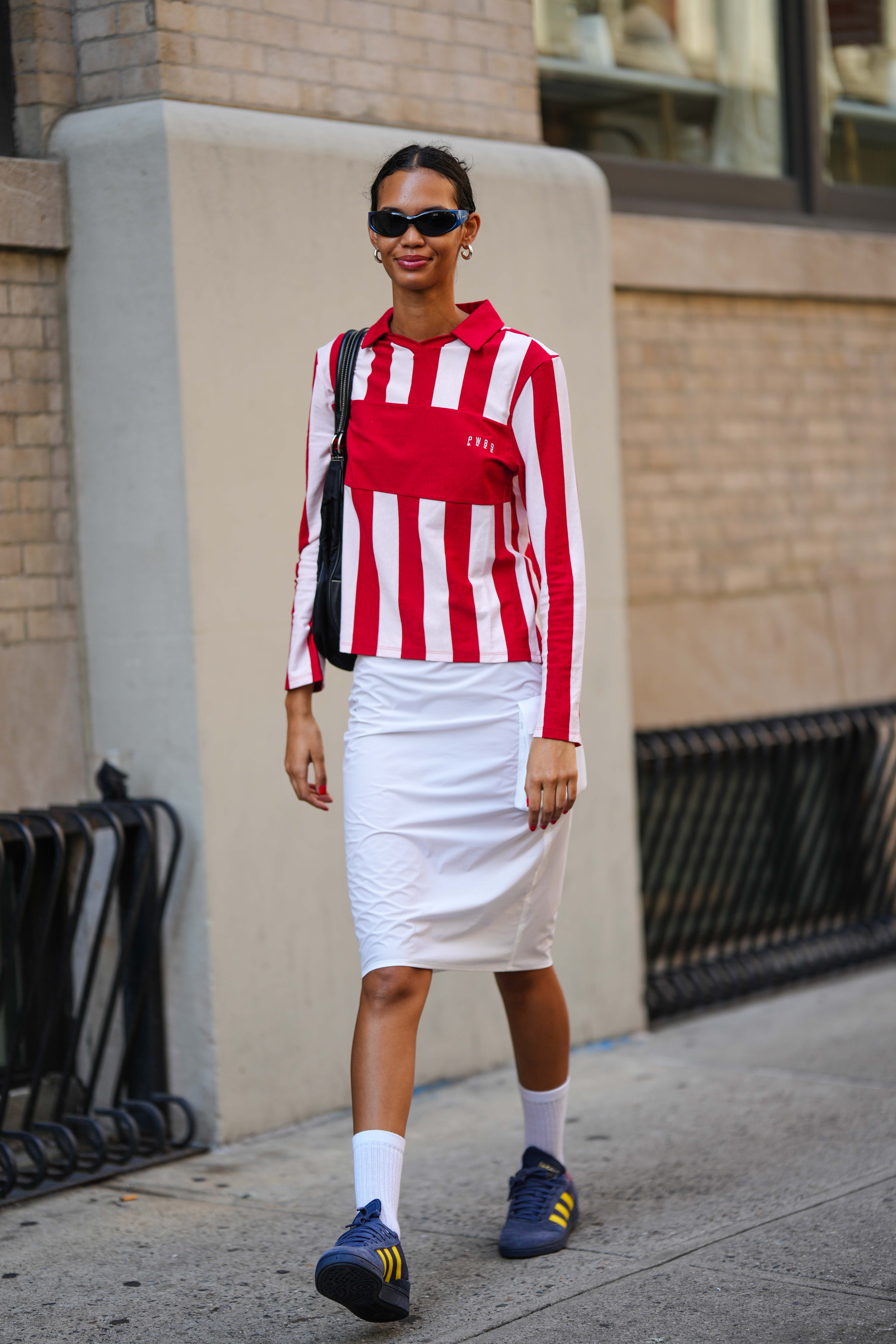 woman wearing red-and-white top, white skirt, and adidas sambas