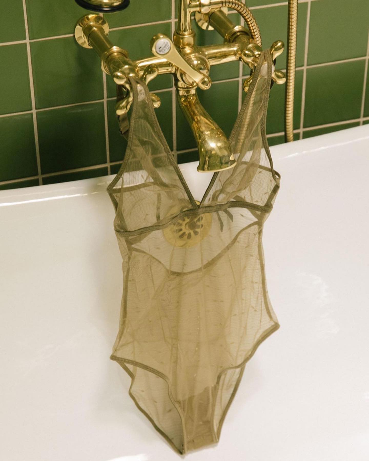 image of a green Else Lingerie bodysuit in a bathtub