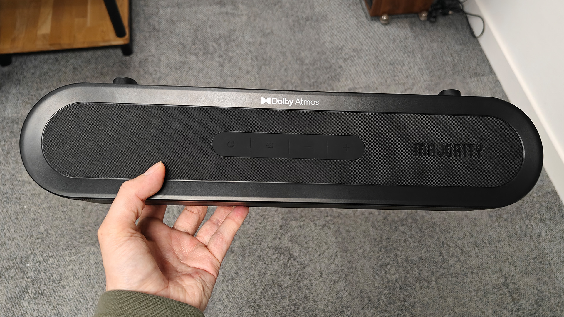 Majority Bowfell Halo Atmos soundbar system, soundbar held in hand above grey carpet