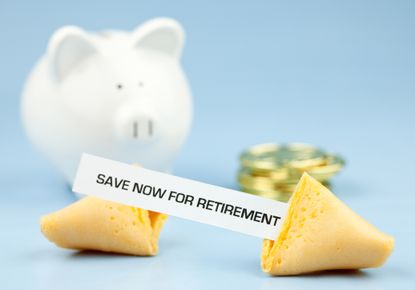 fortune cookie opened with message &quot;save now for retirement&quot; with piggy bank and coins on a light blue background