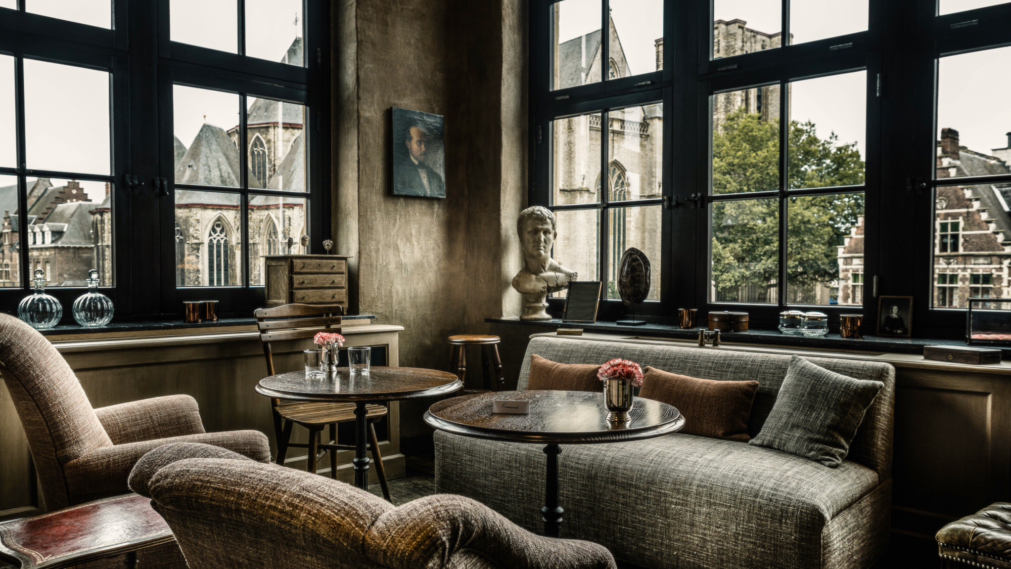 Sofas and small tables in front of corner windows at 1898 Porter&amp;rsquo;s House with view over Ghent, Belgium