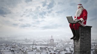 Santa Claus works on a laptop computer atop a high chimney