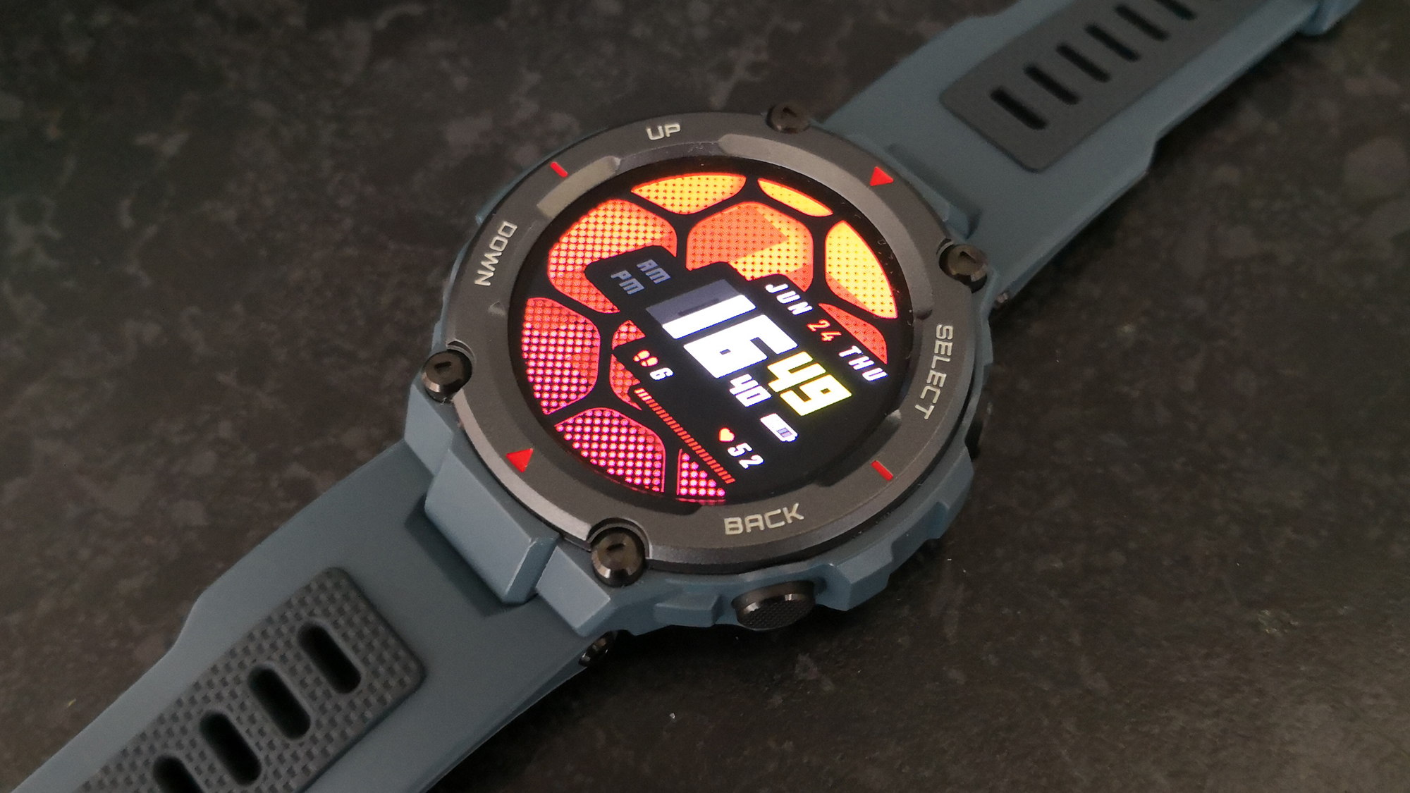 The Amazfit T-Rex Pro watch lies on a table with the face of the watch showing