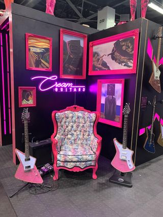 A lavish throne, flanked by two guitars, sits at Cream Guitars' booth at the 2023 NAMM show