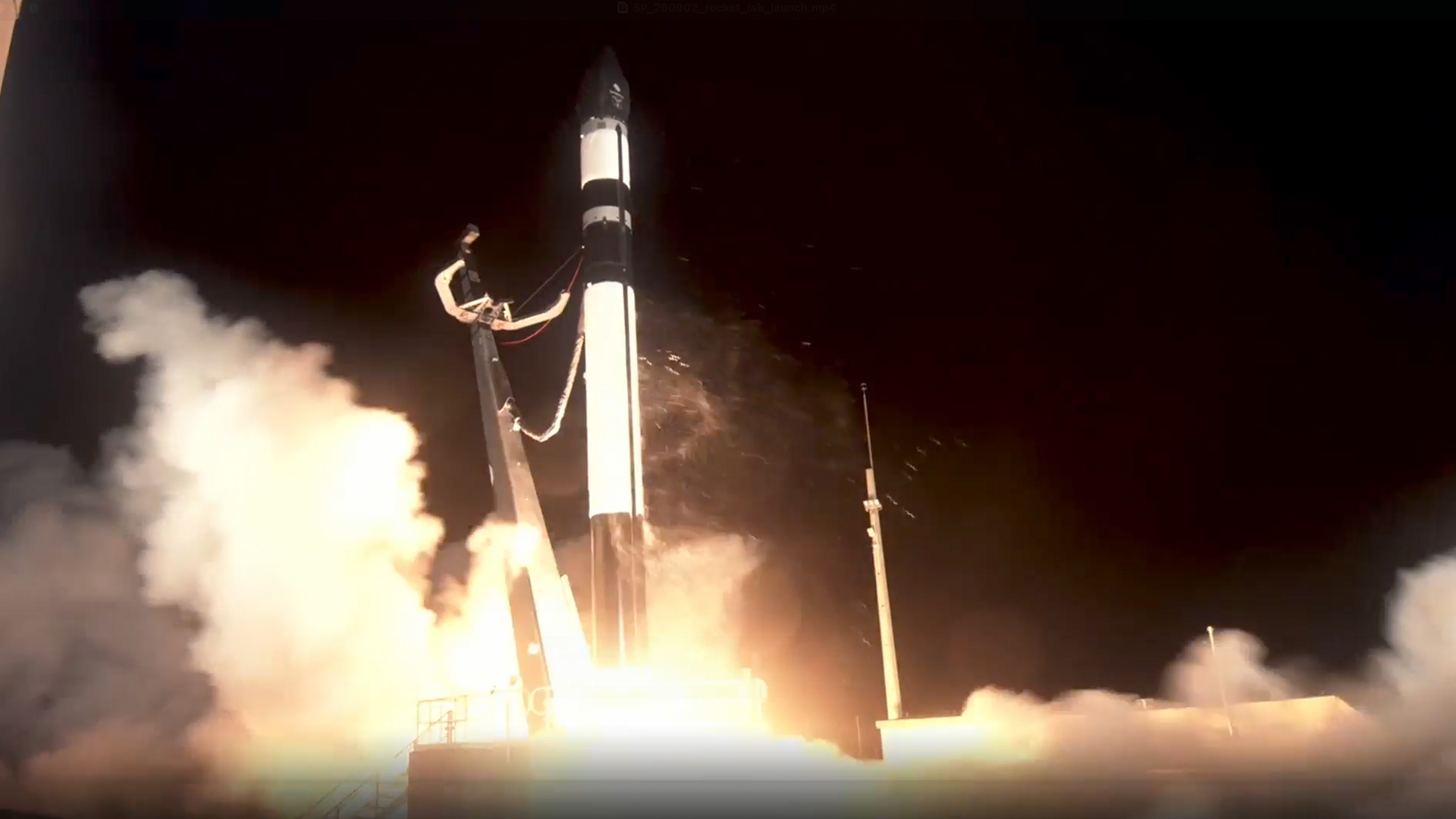a black and white rocket lifts off above a plume of fire and smoke