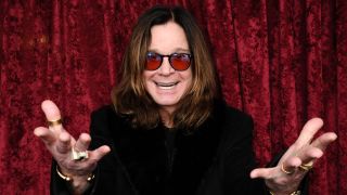 Ozzy Osbourne standing in front of a red curtain