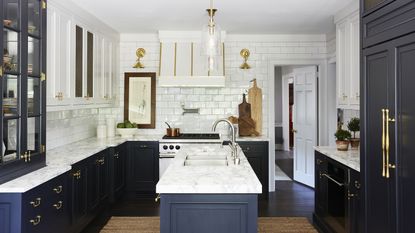 A kitchen with navy cabinetry, white tiled walls and brass hardware