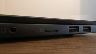 A black MSI Summit E16 Flip Evo laptop sitting on a brown wooden desk