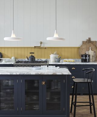Dark blue kitchen cabinetry in a kitchen with yellow and white wall panels