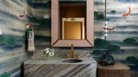 bathroom with floating marble vanity, koi pond mural wallpaper, gold mirror, timber side table, and floating pendant light on one side