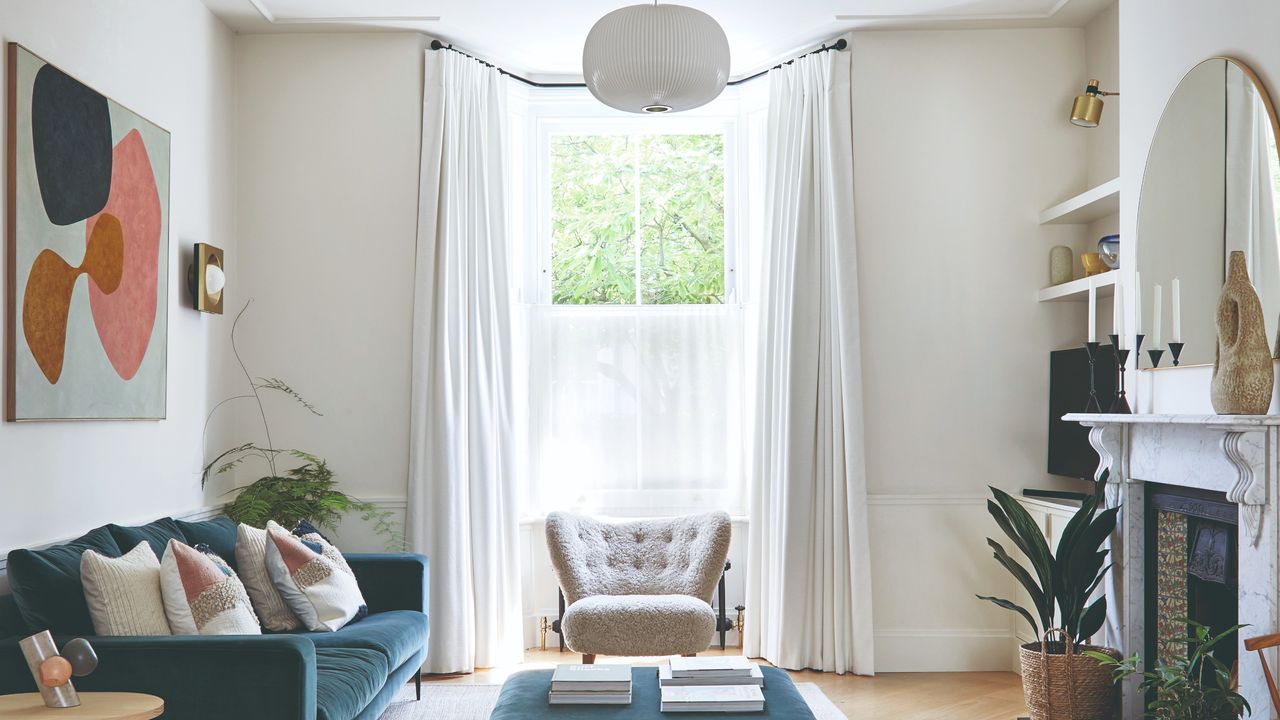 A living room with a high ceiling and a bay window with white curtains