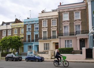 Image of a woman cycling past colorful houses on Primrose Hill, taken on the Sigma 18-50mm f/2.8 DC DN | C Canon RF