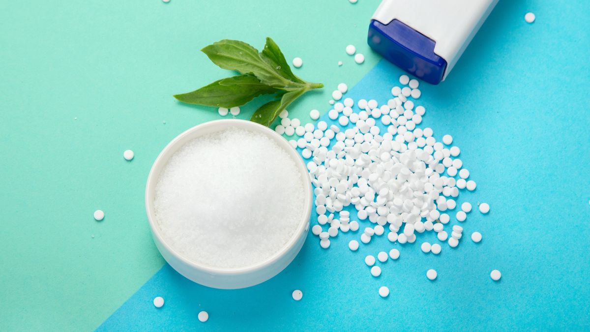 Bowl of sugar and artificial sweetener on blue and green background