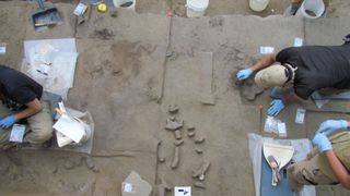 A photo of a rocky excavation site, with light brown rock covered in tools and signs.