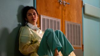 Elodie Yung in medical scrubs sitting on the floor crying in The Cleaning Lady