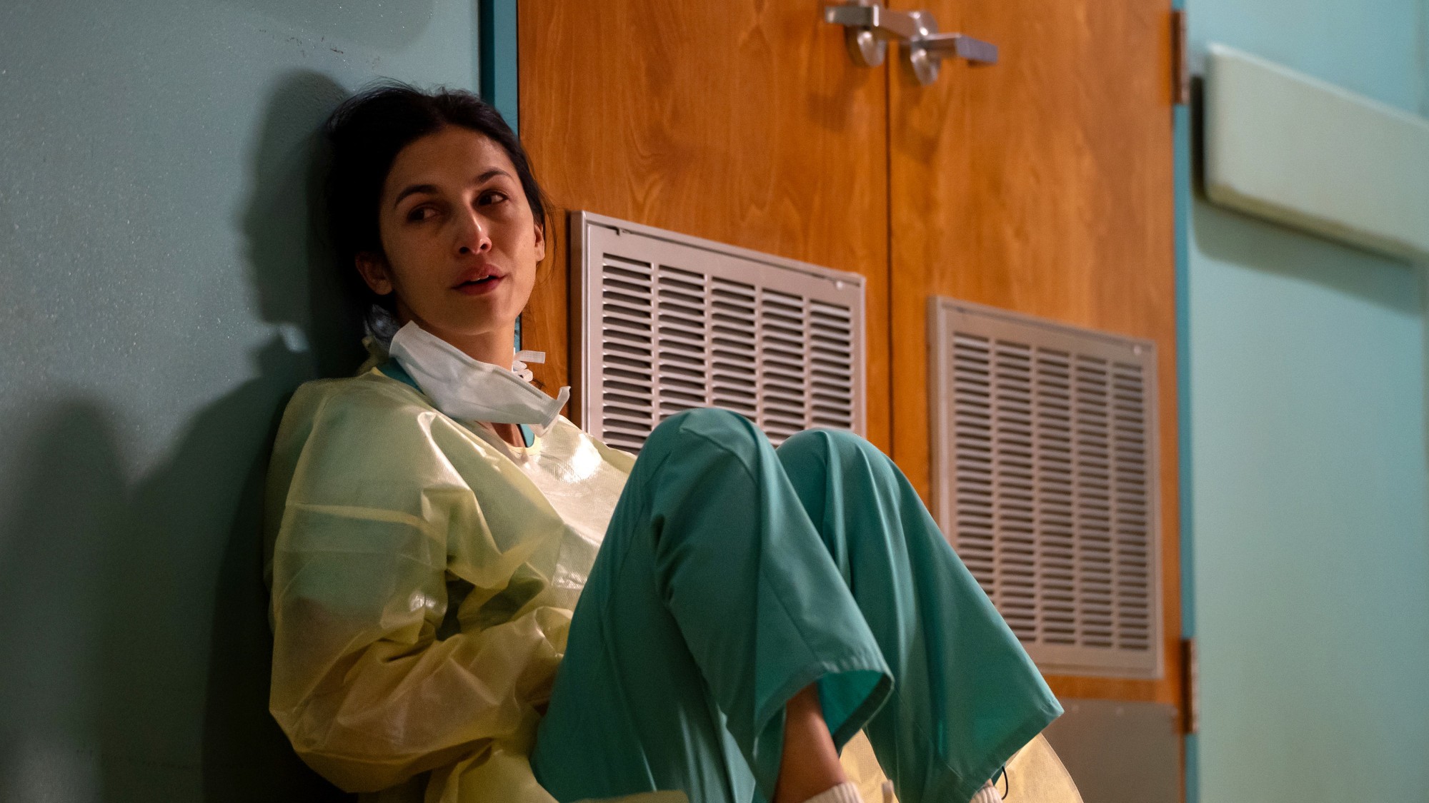 Elodie Yung in medical scrubs sitting on the floor crying in The Cleaning Lady