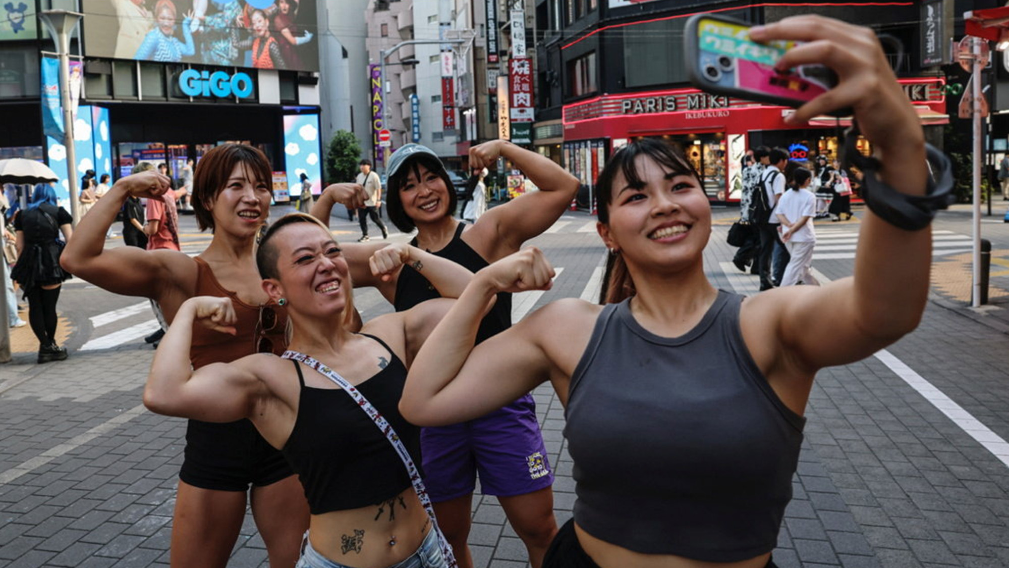 Staffers from the fitness-themed Muscle Girls bar pose for a group selfie in Tokyo, Japan