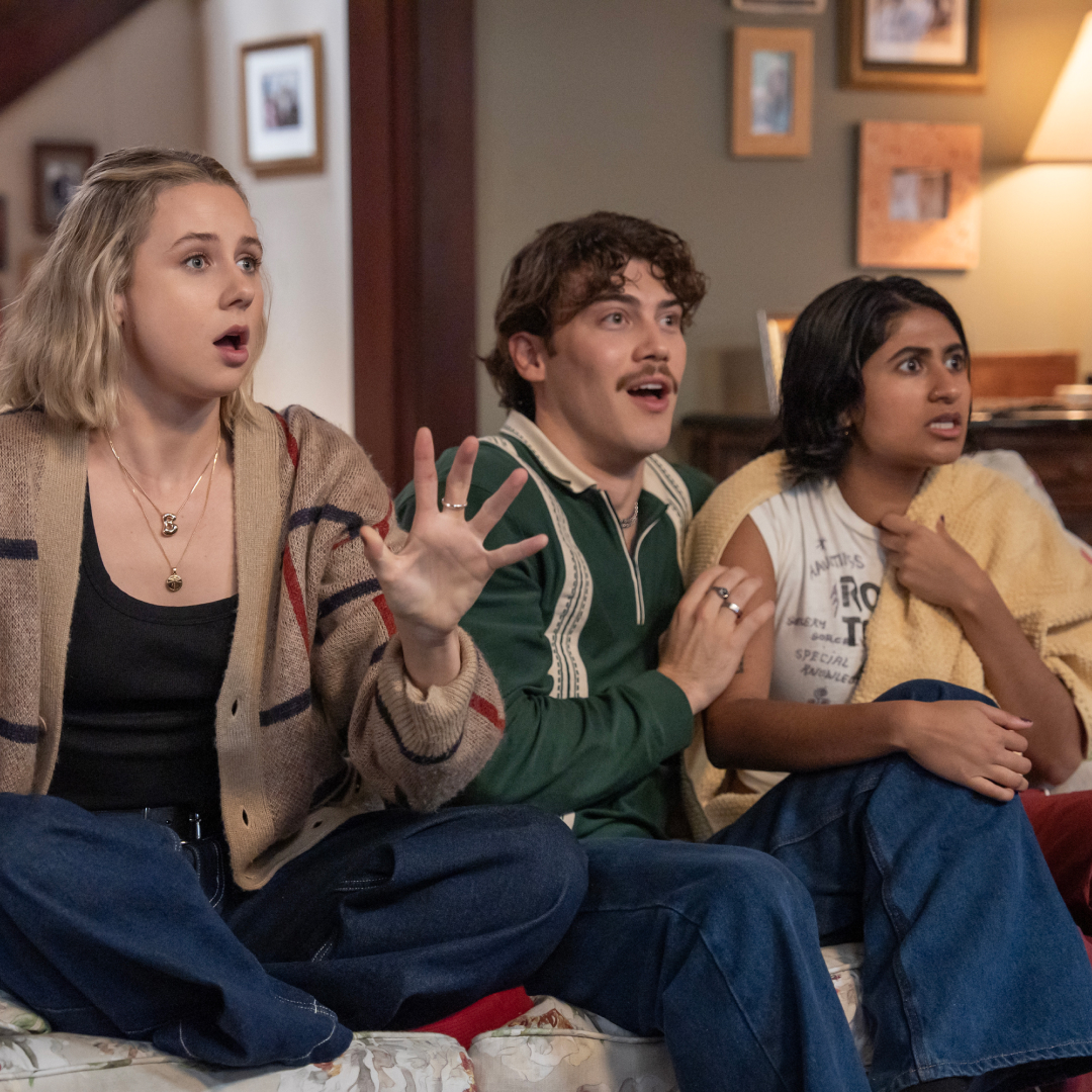 Three people (Lucy Freyer as Billie, Jack Innanen as Paul Baker, Amita Rao as Issa) look surprised while sitting on a living room couch, in &#039;Adults&#039;.