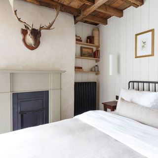bedroom with white walls, alcove and stag's head decoration