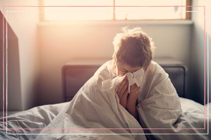 Little boy sick with scarlet fever lying in bed and blowing nose