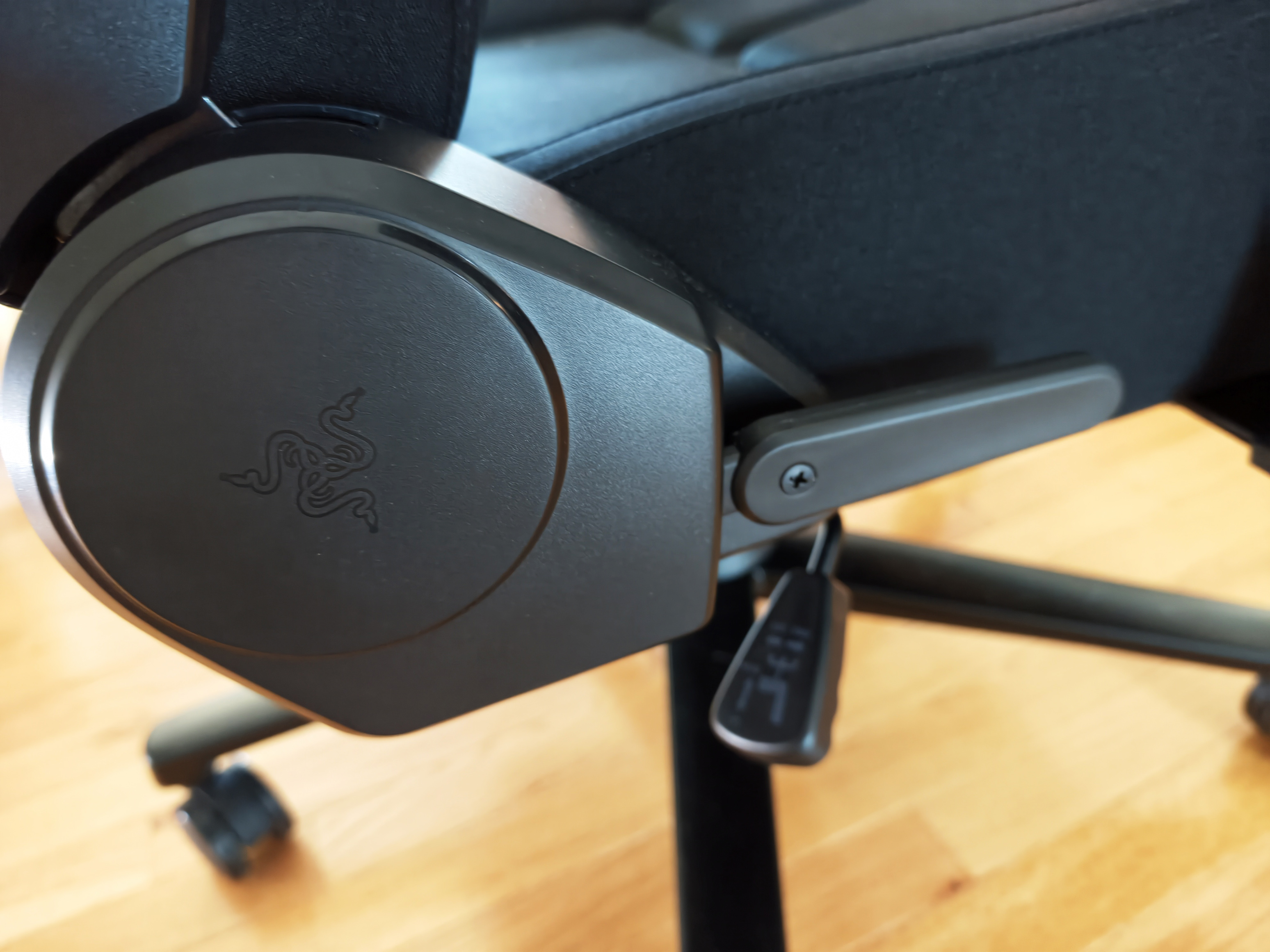 Side view of the chair's recline lever and plastic adjustment mechanism cover, which is embossed with the triple-headed snake Razer logo.