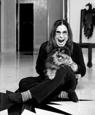 Ozzy Osbourne sat on floor with a dog in black and white