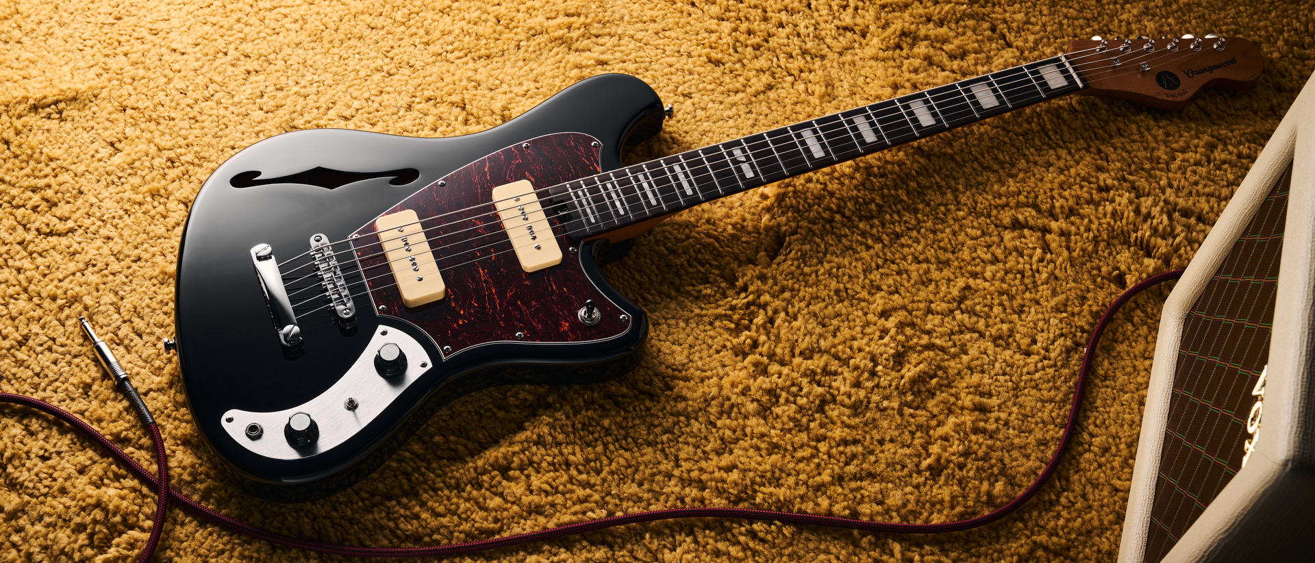 An Orangewood Del Sol Baritone guitar lying on a yellow rug