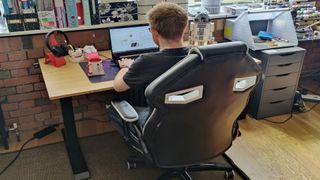 Image shows a person sitting at the FlexiSpot E7 desk, working on a laptop.