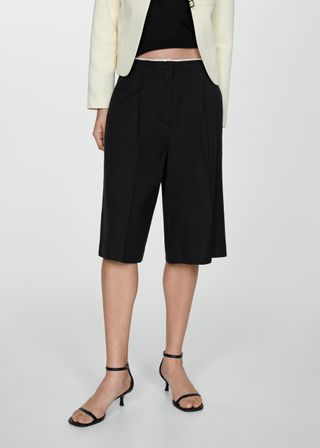 A Model Wears Black Bermuda Shorts 