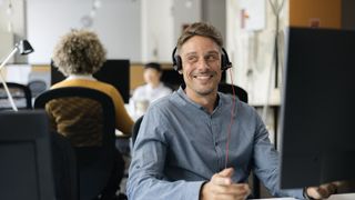 Man sitting with headset on at desk in office