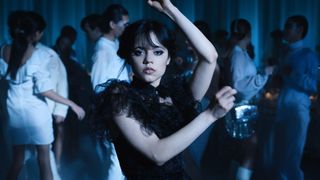 Wednesday Addams holder en dansepositur mens hun ser inn i kamera i sin egen solo-serie på Netflix.