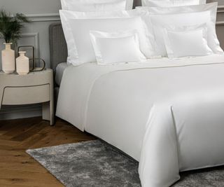 Frette Ultimate Sheet Set on a bed against a gray wall.