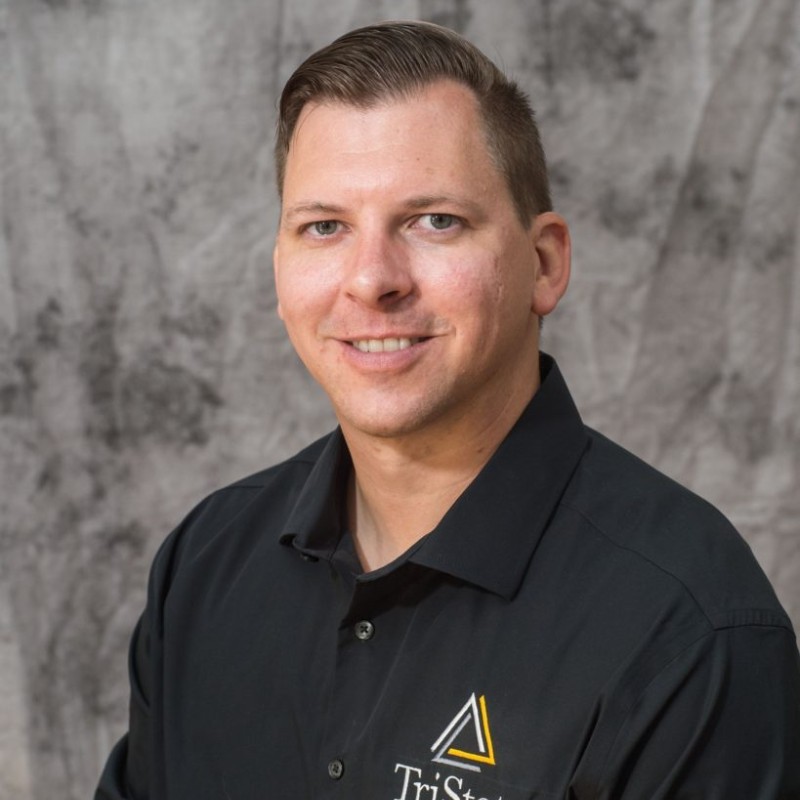 Bert is a white man in a black polo shirt, pictured in a professiona headshot on a gray background