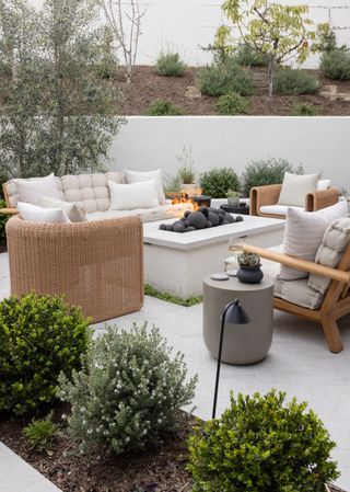 Rectangular fire pit with rattan seating by Garden Studio Design